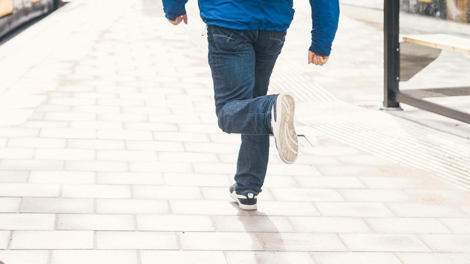 En person som springer i vanliga vardagskläder, fotograferad bakifrån