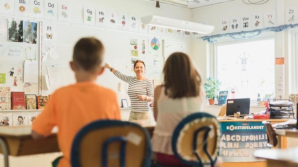 Lärare pekar på whiteboard-tavla när hon undervisar sina elever i ett klassrum