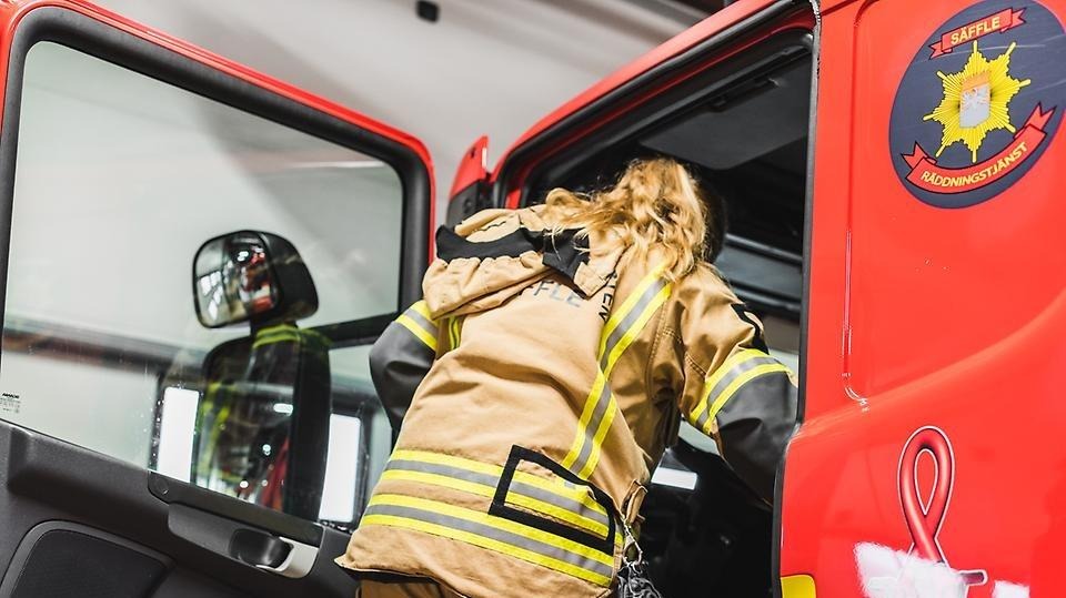 Personal från räddningstjänsten kliver in i en brandbil