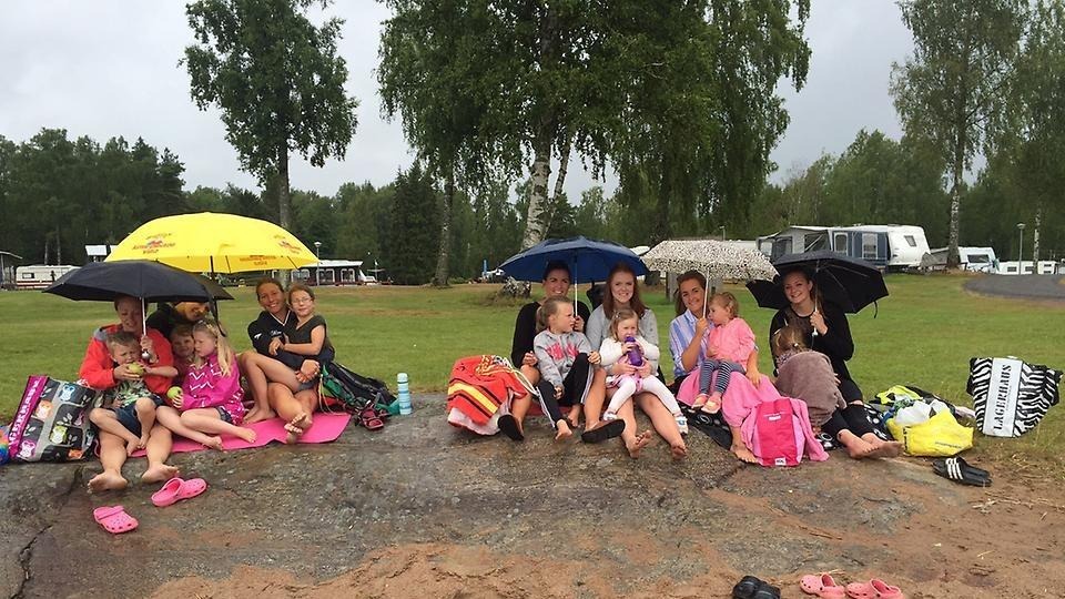 Bild på ett stort glatt gäng med barn och vuxna under paraplyer