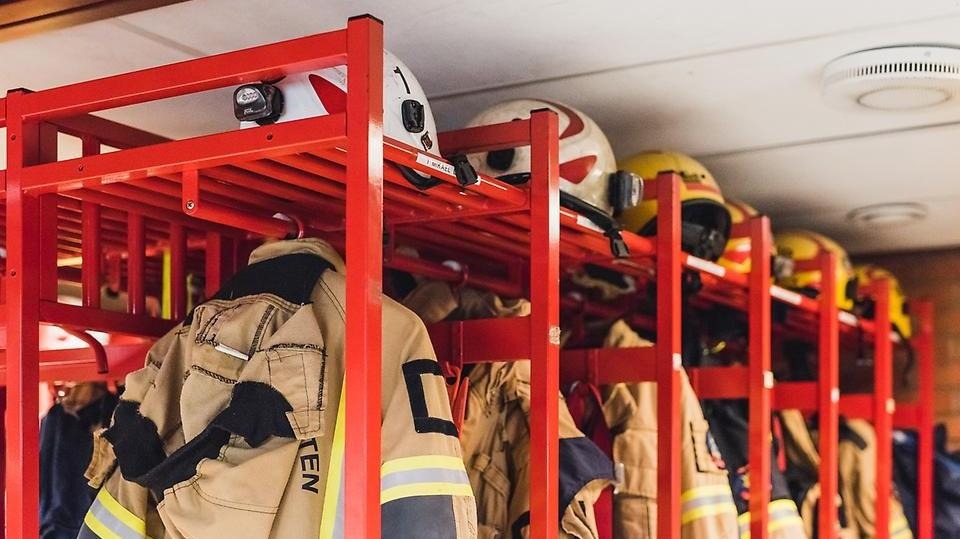 Räddningstjänstens arbetskläder och utrustning hänger i ett omklädningsrum