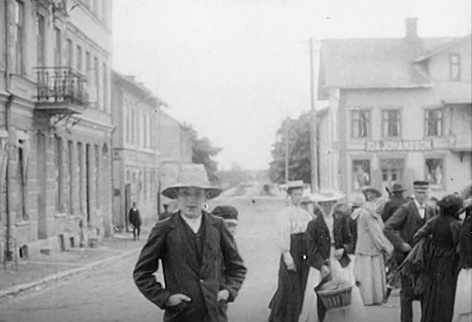 Svartvit stillbild på ung gosse stående på Stortorget i filmen från 1908